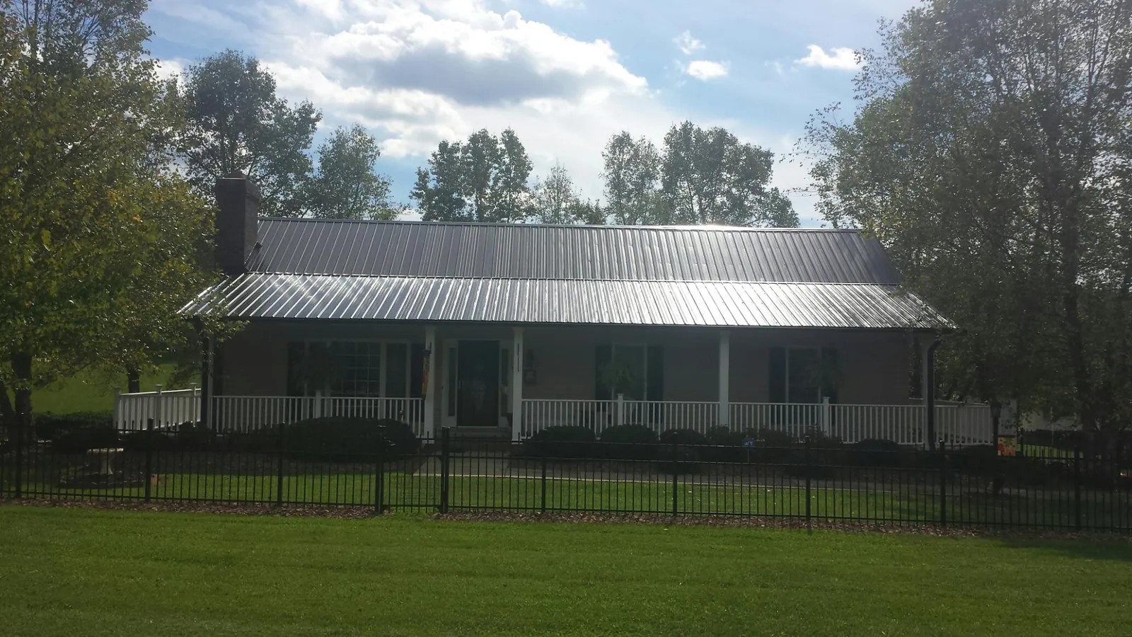 Gray metal roof on a brick ranch with a full width front porch — Gutter Guard Installation work by our crew in Sherman